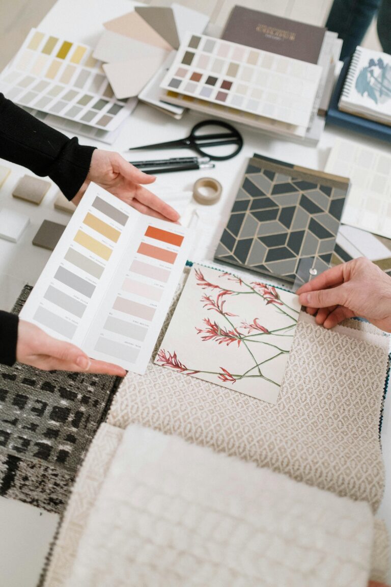 Top view of hands selecting color palettes and textile samples for interior design.